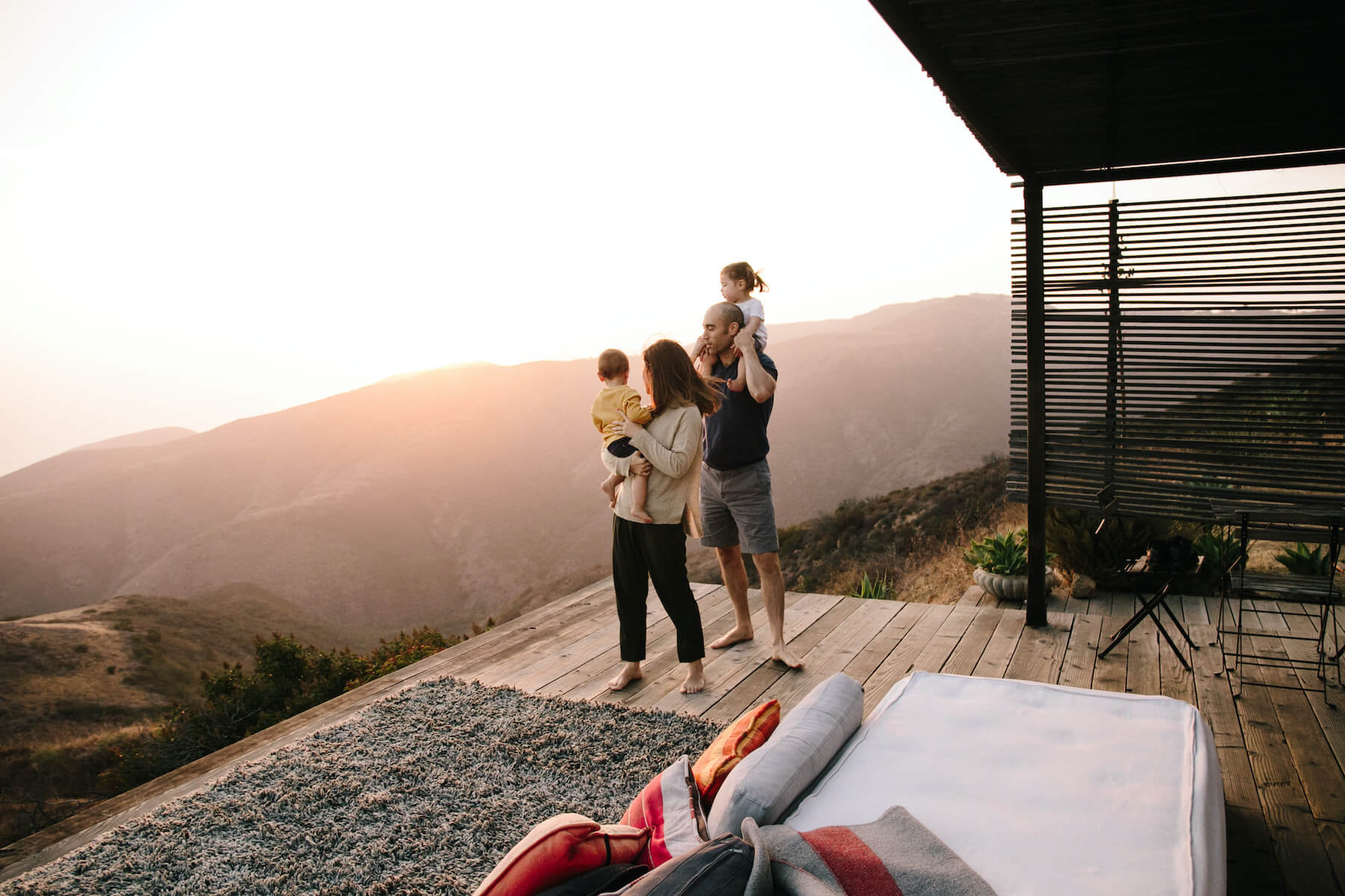 A family looks out at the rolling hills from a patio at sunset.